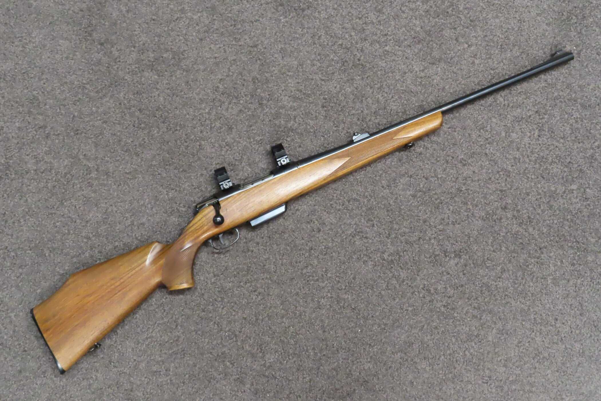 High-quality rifle with wooden stock, scope mounts, ideal for precision shooting and hunting.