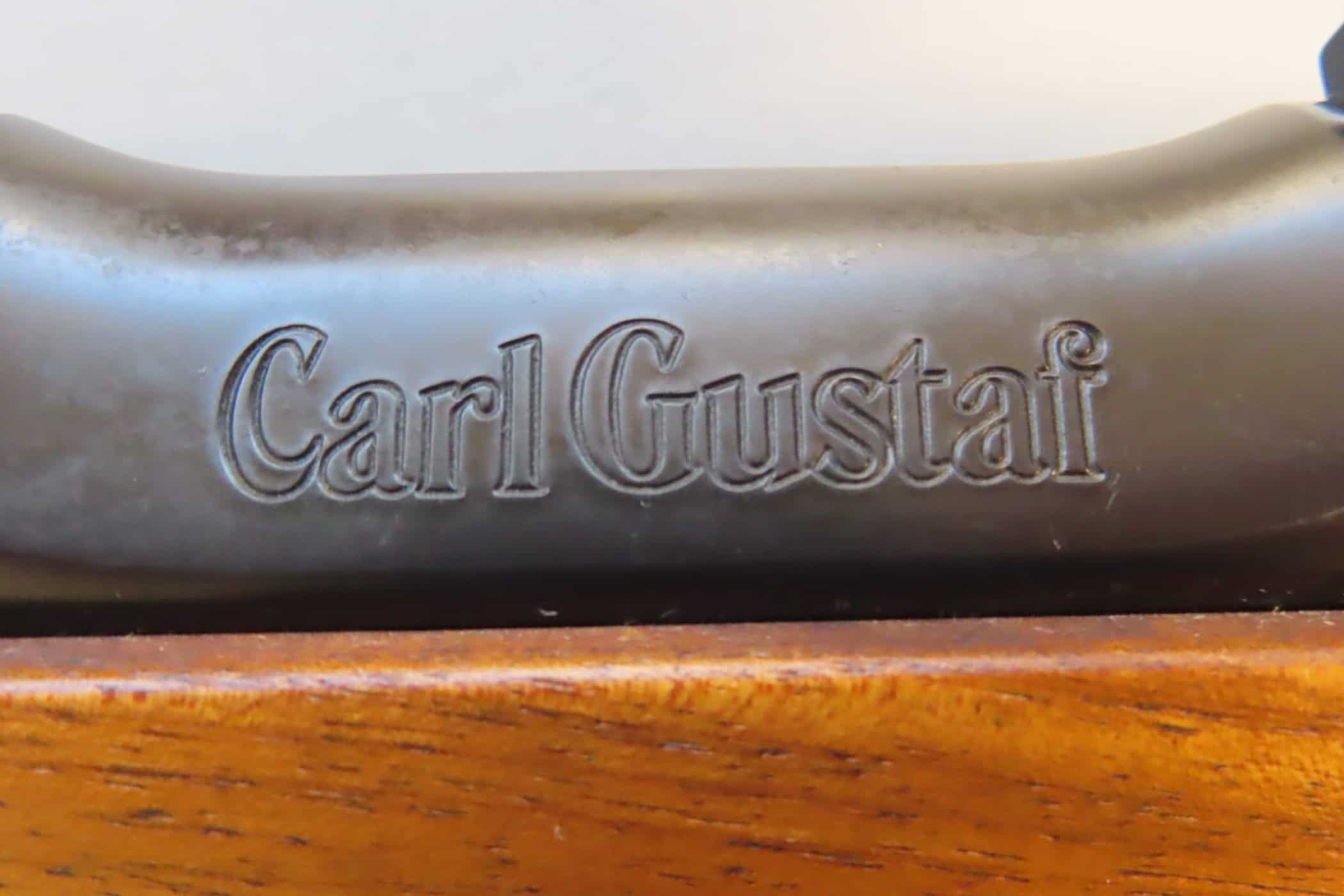 Close-up of engraved "Carl Gustav" on firearm component, highlighting historical firearm branding.