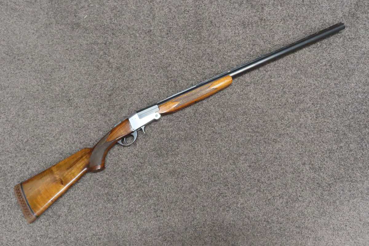 Vintage bolt-action hunting rifle on grey carpet floor.