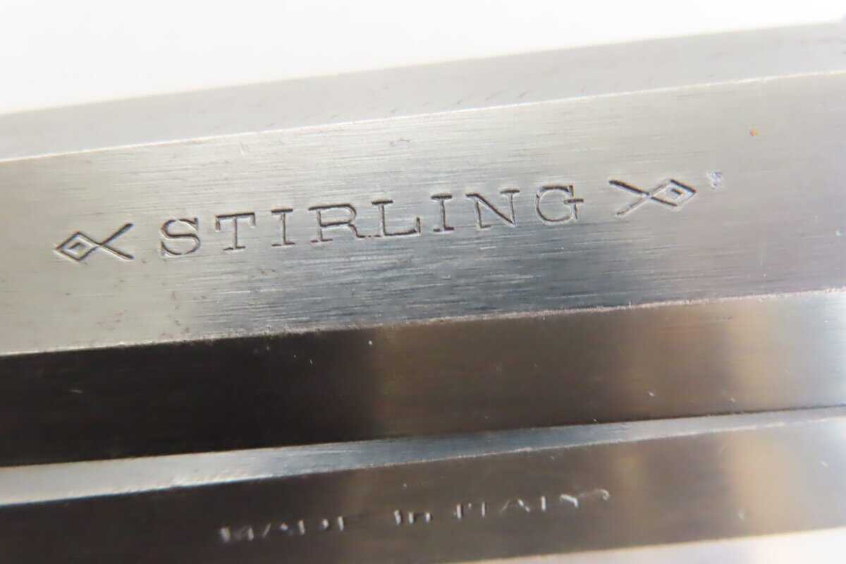 Close-up of a metal firearm part engraved with "Stirling" and decorative symbols.