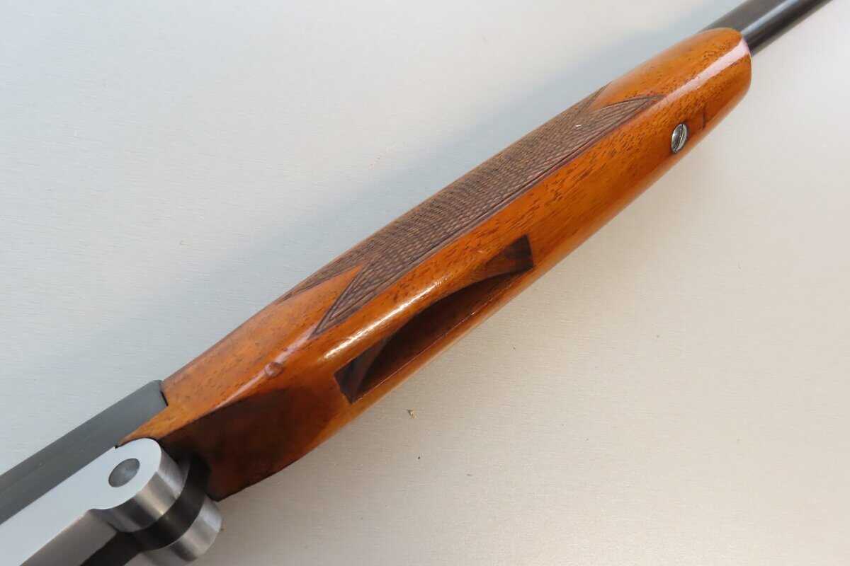 Close-up of vintage rifle stock featuring polished wood and detailed checkering for precision shooting.