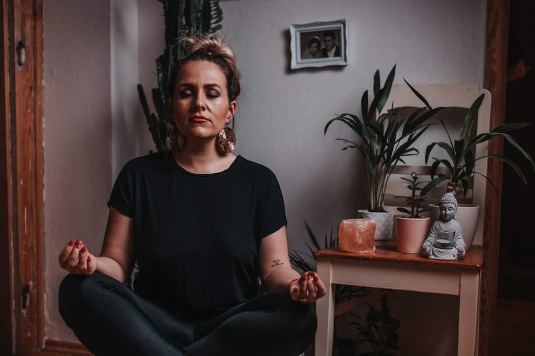 Woman meditating with plants and Buddha statue