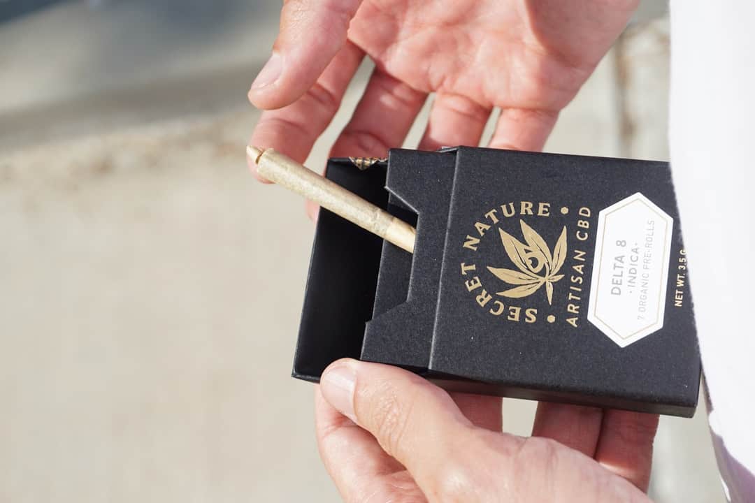 Hand holding black CBD pre-rolls box