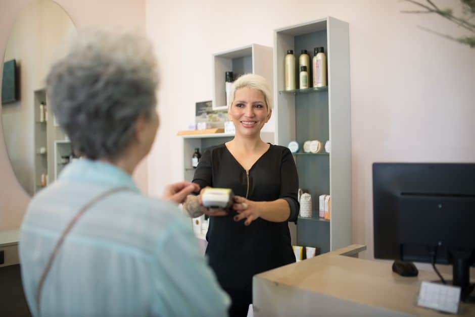 Blonde cashier handing payment terminal to customer