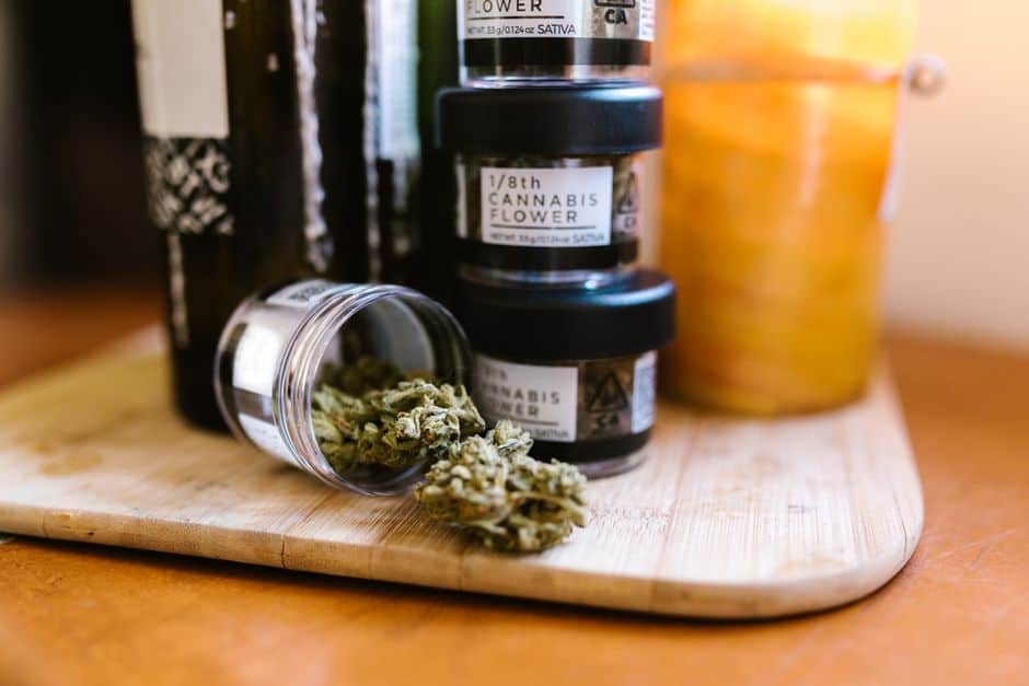 Cannabis flower jars and buds on wooden board