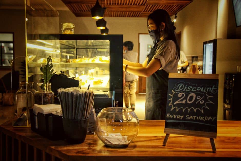 Barista behind counter with 20% discount sign