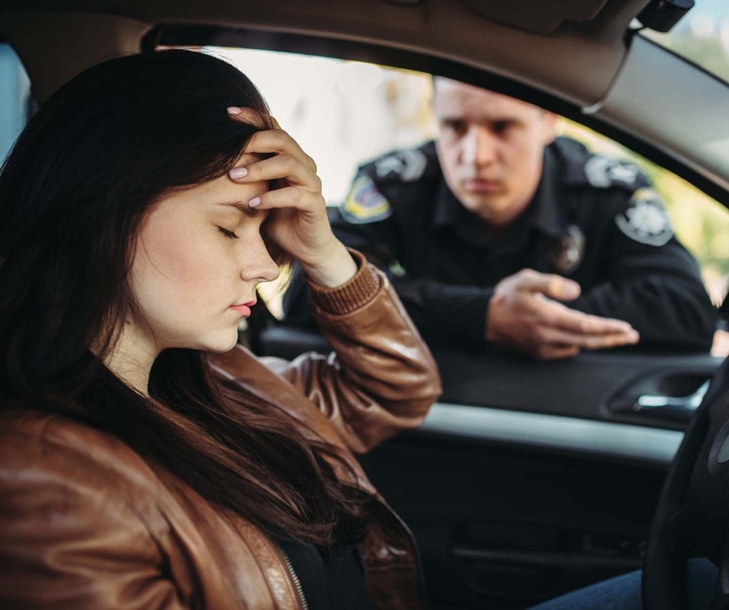Woman distressed after car accident with police officer outside vehicle.