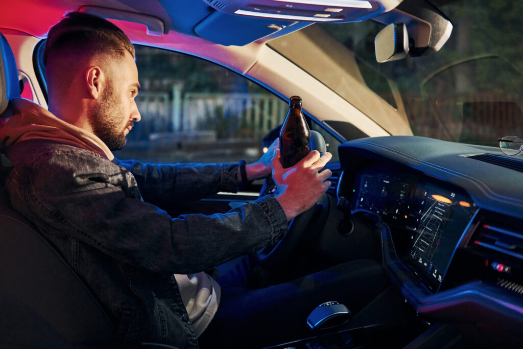 Black and red police lights. Dont drink and drive. Side view of handsome unshaved man in fashionable clothes inside his automobile.