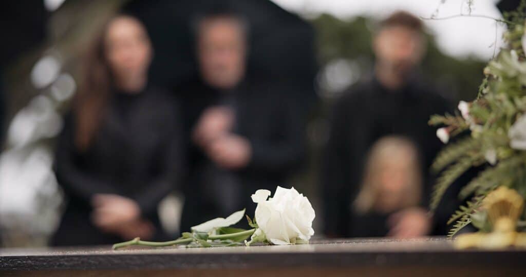 Funeral service image with white flower, representing condolences and support.