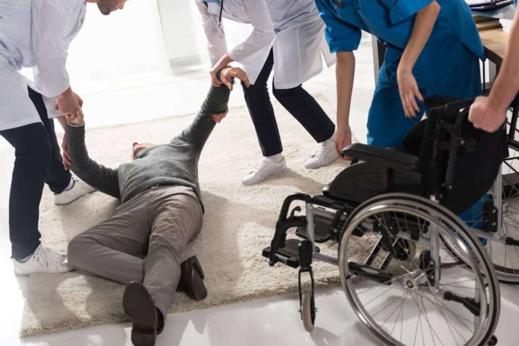 Person injured on the floor with medical team assisting, Mesa slip and fall attorneys nearby.