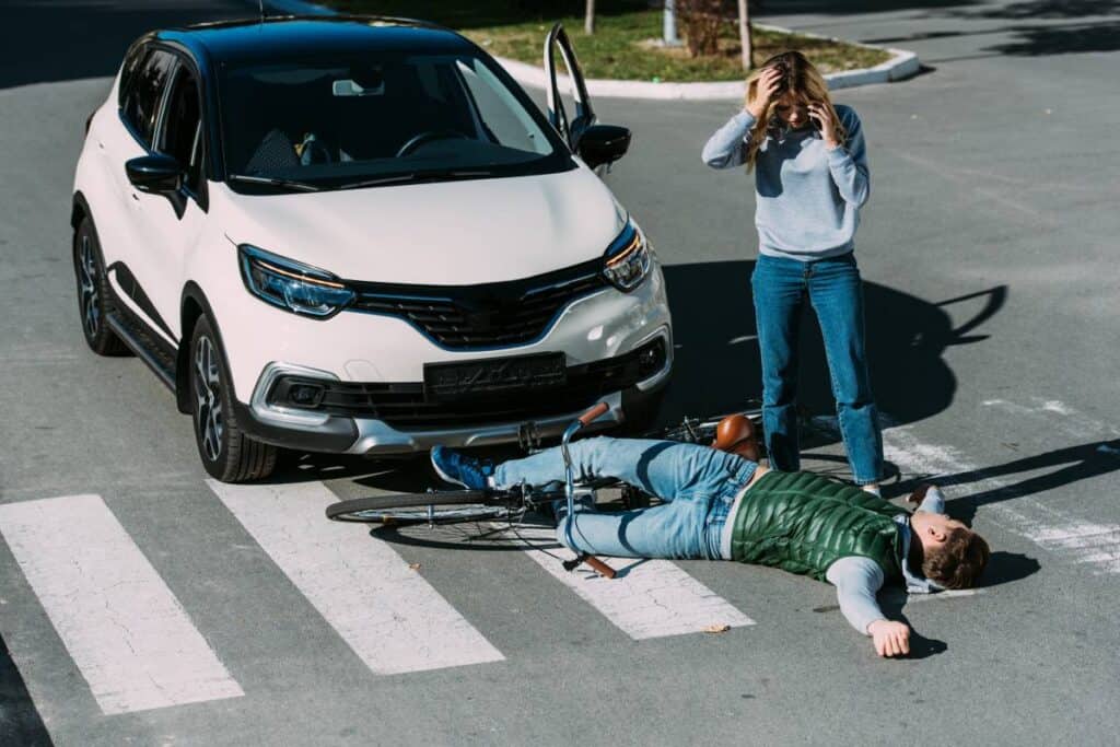 Car accident with pedestrian and cyclist on crosswalk in daylight.
