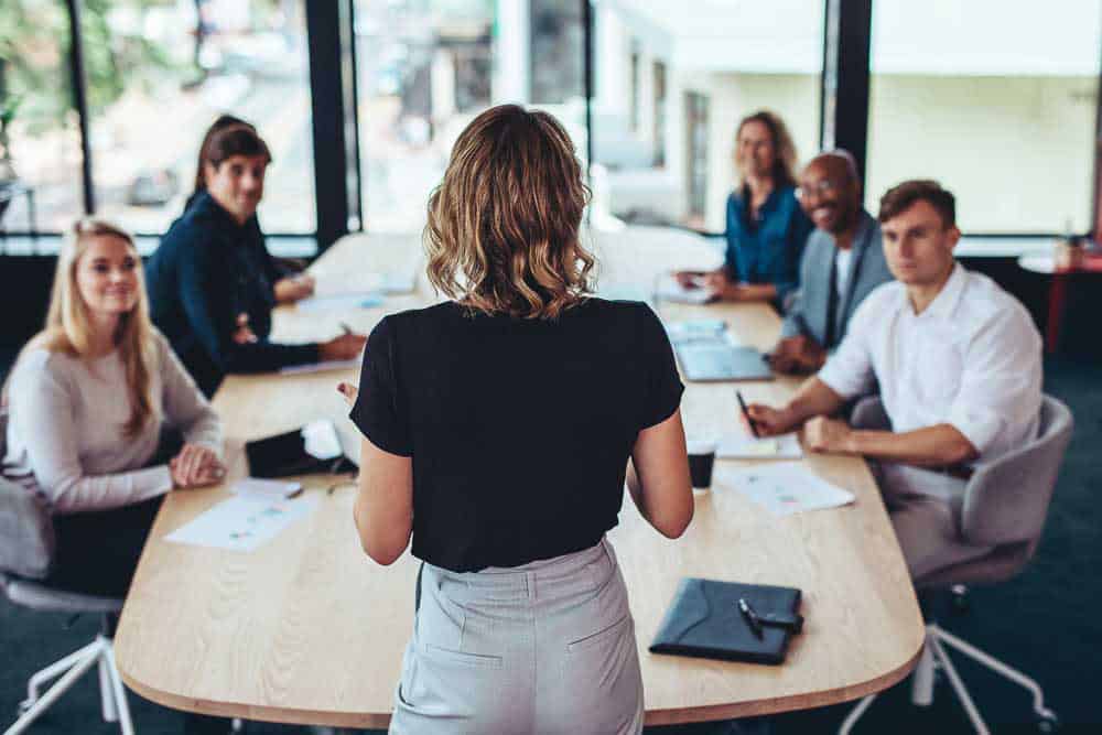 Executive standing at the head of a boardroom table leading a leadership decision discussion.
