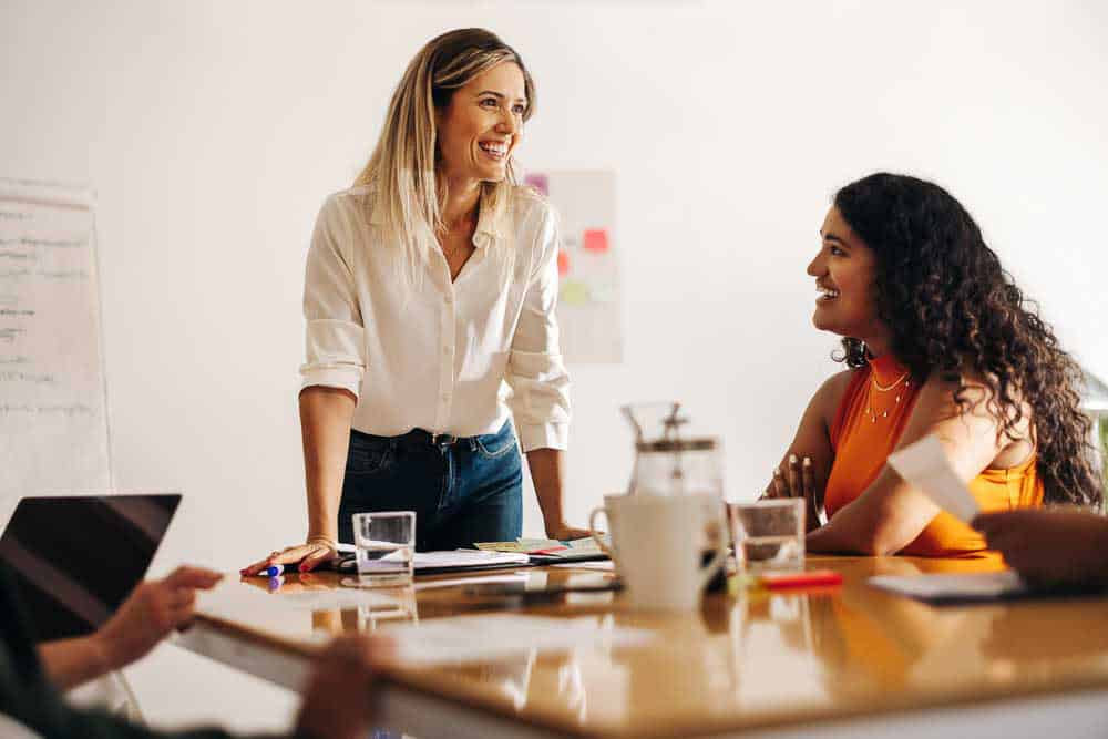 Founder-style leader standing at a table guiding a strategic people discussion.