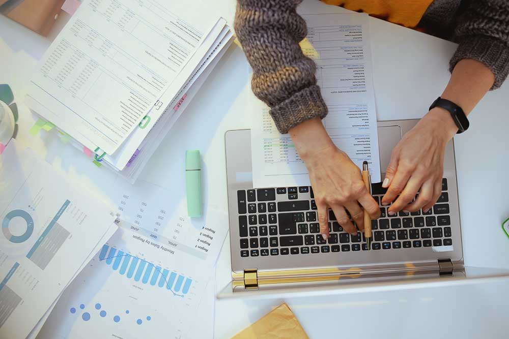 Hands working on a laptop reviewing reports and data related to leadership and people risk analysis.
