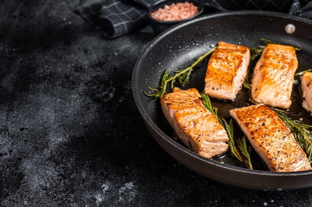 Grilled Salmon Fillet Steak in a pan. Black background. Top view. Copy space