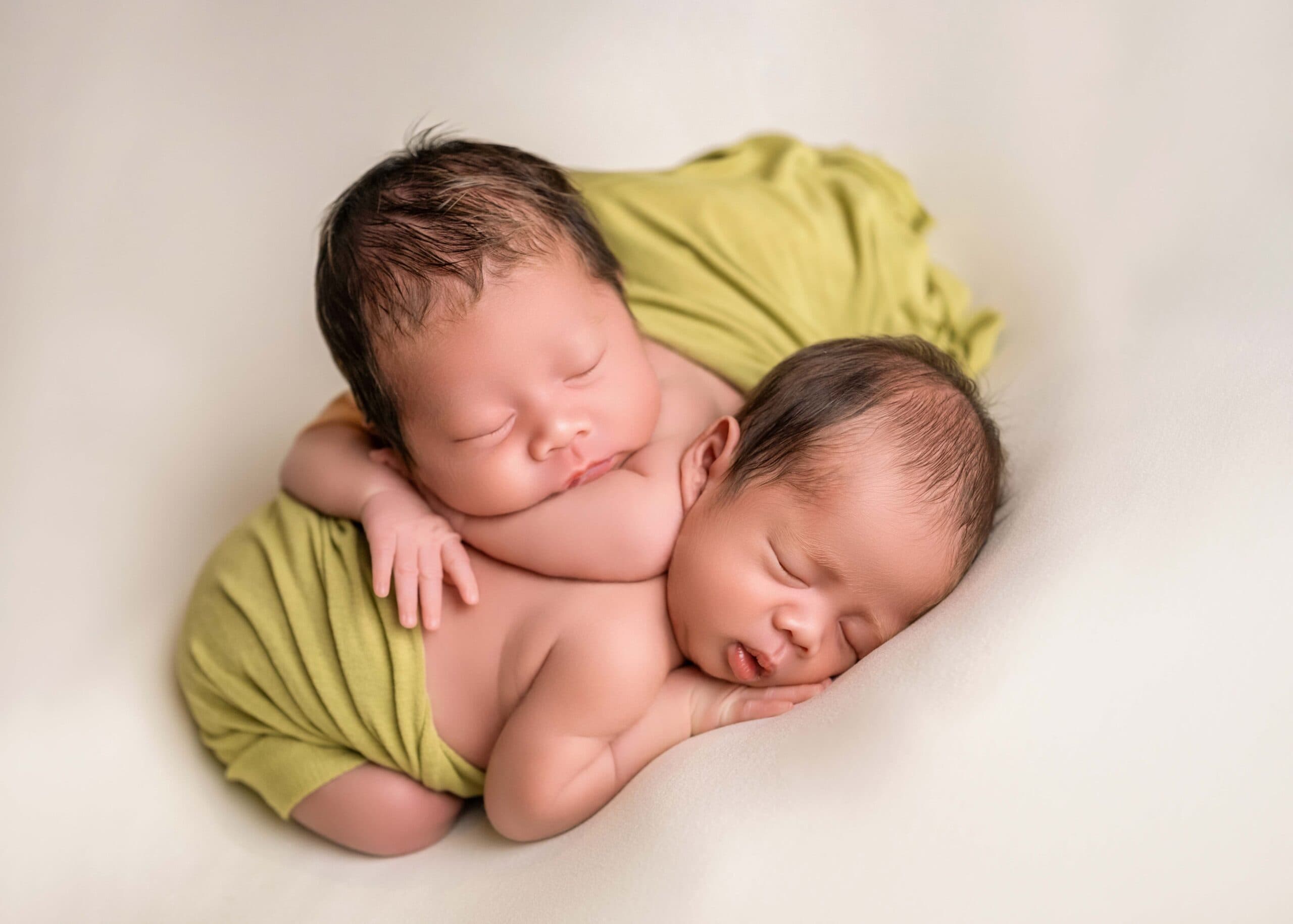 Twin newborn babies taking newborn photo with Little One Photography