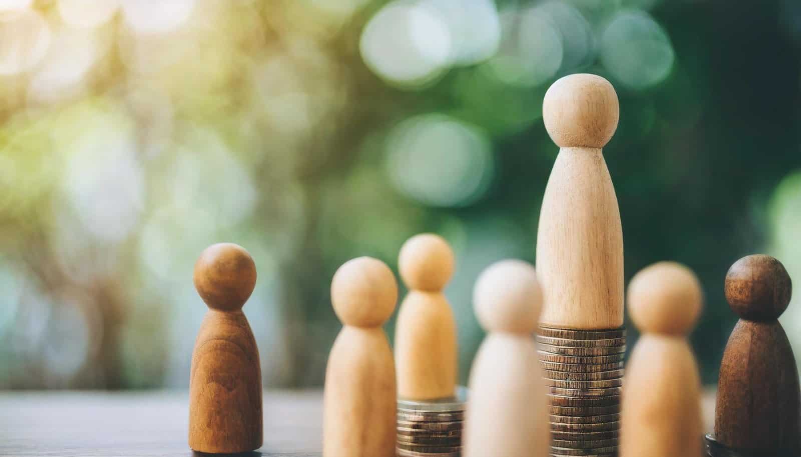 Wooden figures on stacked on coins.