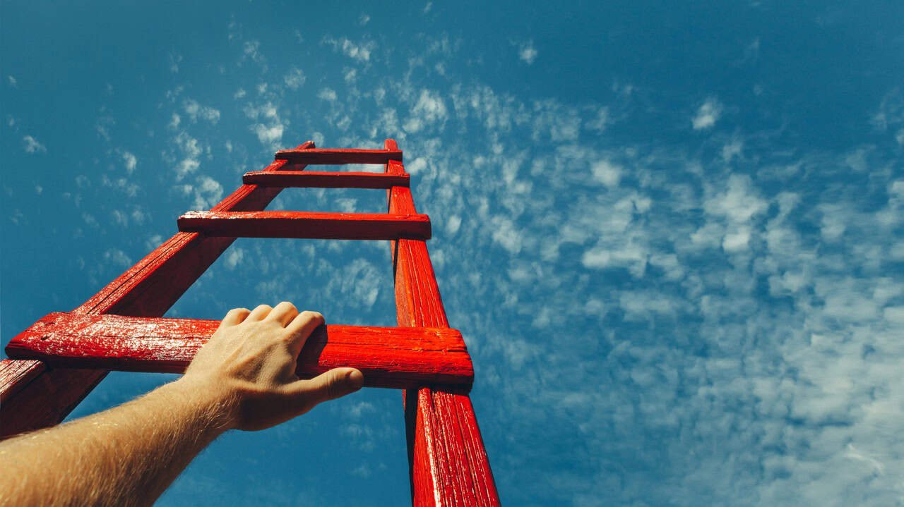 Climbing a red wooden ladder towards the sky with scattered clouds, symbolizing growth, ambition, and reaching new heights in life or career.