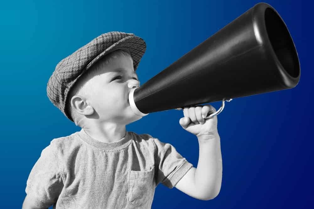 Boy with a megaphone, child shouting through a loudspeaker against a blue background, inspiring leadership, communication, and kids' voice concept.