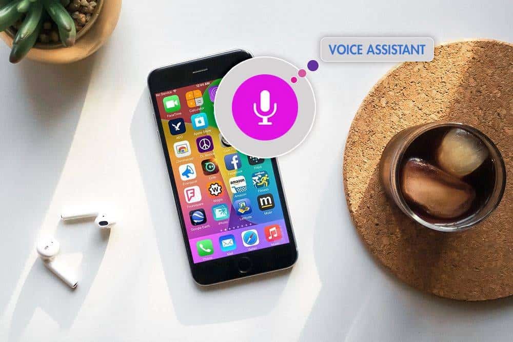 Smartphone with voice assistant icon, Apple AirPods, and iced coffee on a white desk, highlighting mobile technology and digital assistant features.