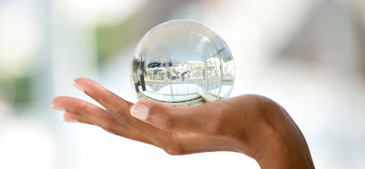 Crystal ball held in hand reflecting cityscape and sky, symbolizing vision and insight, captured in professional photography for personal branding or creative portfolio.
