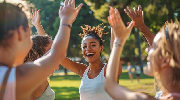 Joyful diverse group of women celebrating outdoors with high-fives in a park, emphasizing wellness, happiness, and community, ideal for health and lifestyle content.