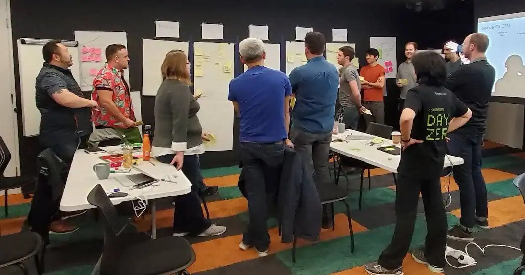 Collaborative team meeting in a modern conference room with whiteboards, sticky notes, and presentation screens for business strategy and project planning.