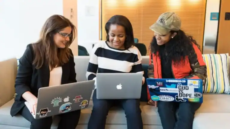 Three women using laptops to participate in free bible studies for women.