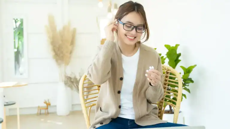 Woman smiling while putting earbuds in her ears