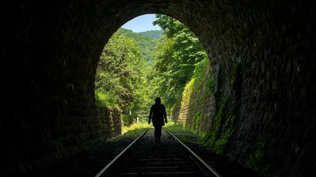 A woman walking through a dark train tunnel