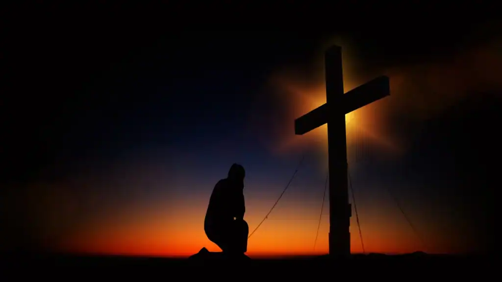 A person kneeling in front of a cross A person kneeling in front of a cross