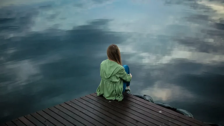 A Christian woman sitting on a dock looking at a lake facing injustice