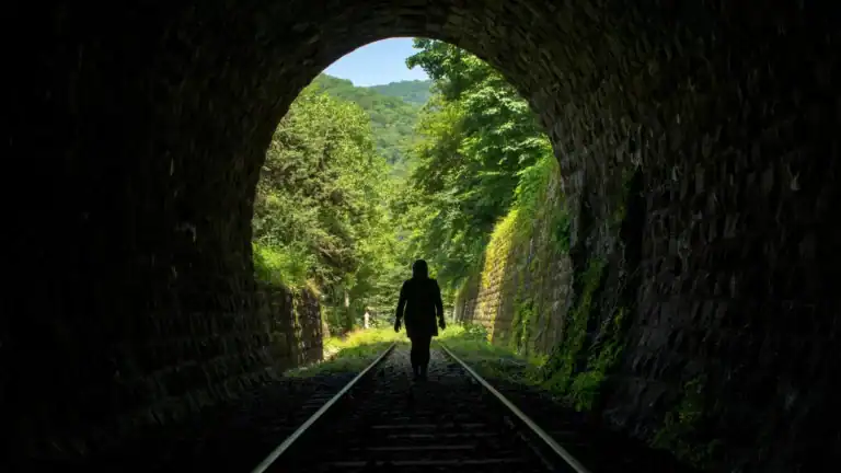 A woman walking through a dark train tunnel