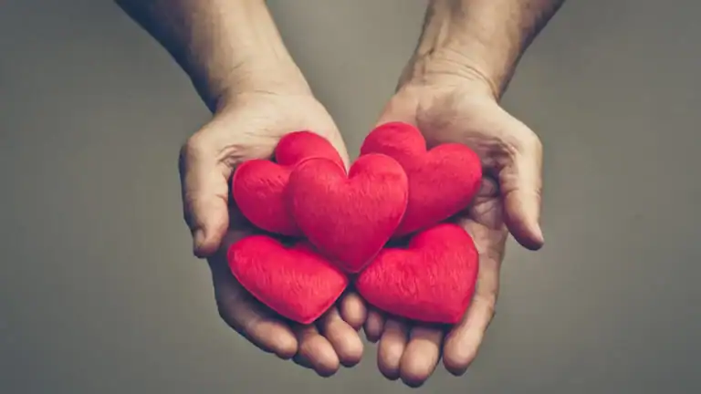 A man's hands holding red hearts.
