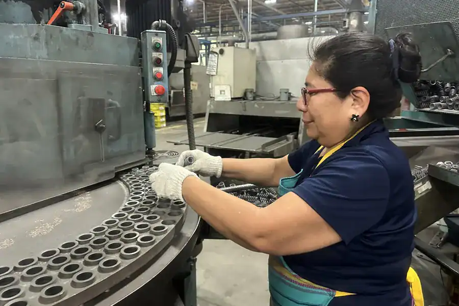 Chuhatsu North America, Inc. factory worker inspecting metal components in an industrial manufacturing plant.