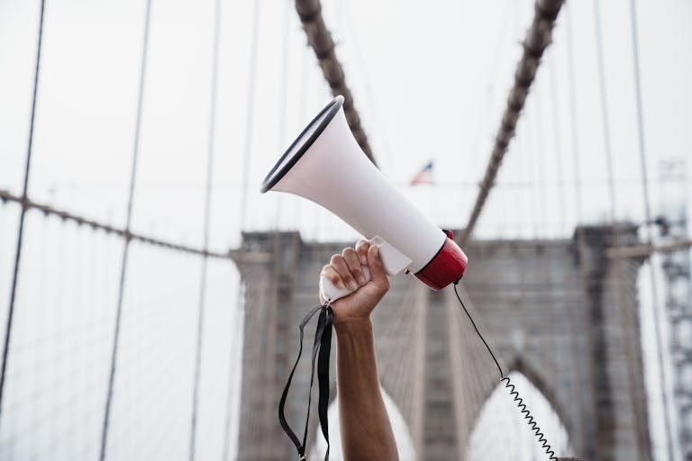 A protester breaking the silence by raising a megaphone during a demonstration on the iconic Brooklyn Bridge.
