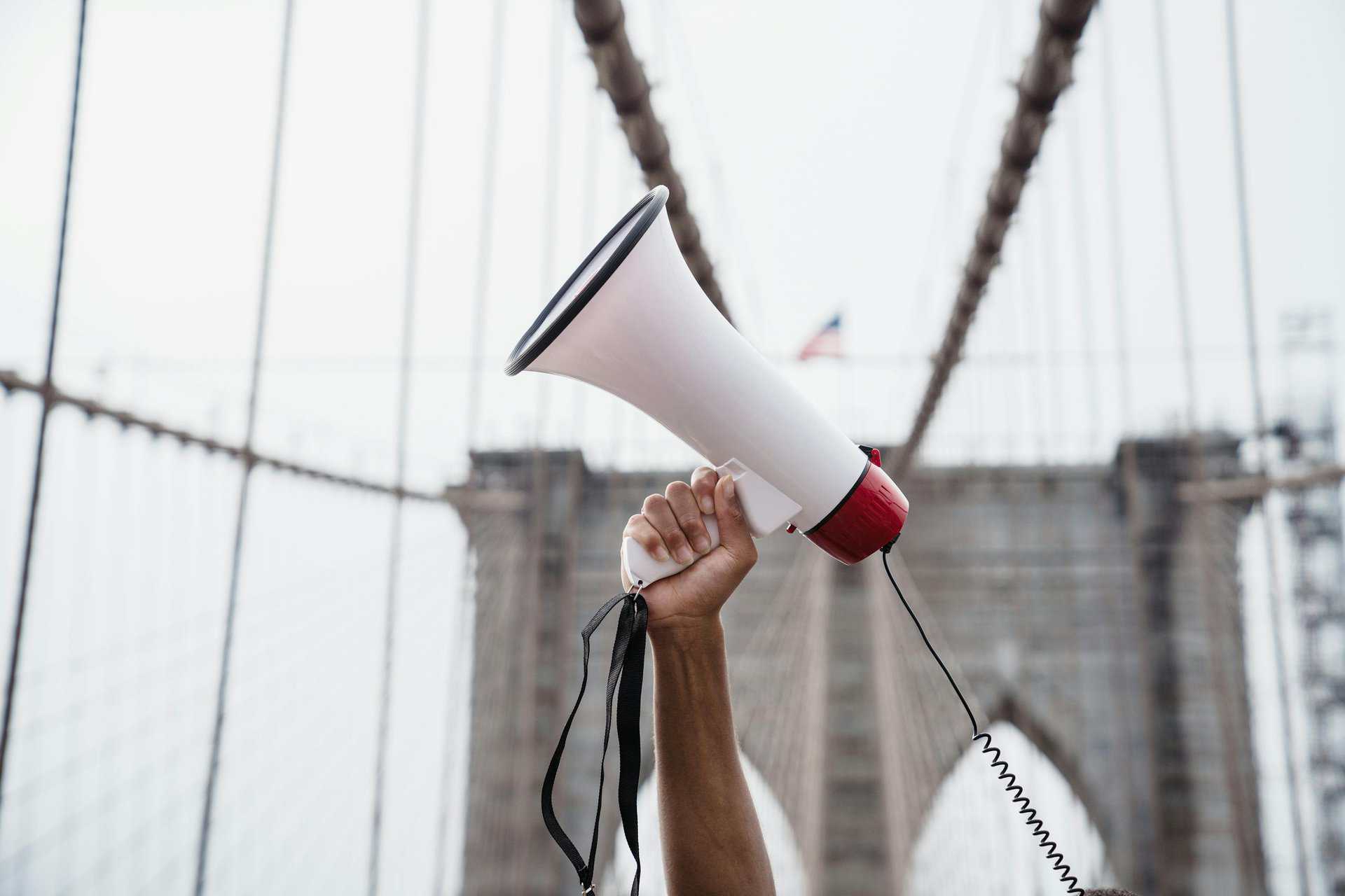 A protester breaking the silence by raising a megaphone during a demonstration on the iconic Brooklyn Bridge.