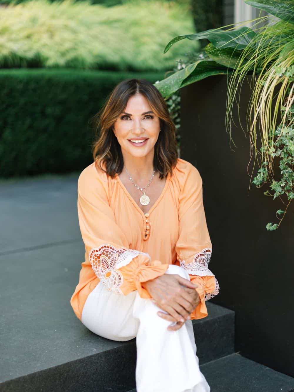 Photo of Cindy in light orange shirt sitting outside