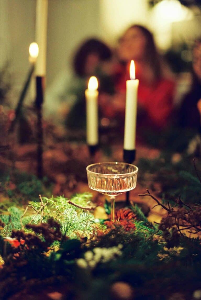 Photo of candlelight on table with a group of people representing ways to help with trauma triggers during the holidays