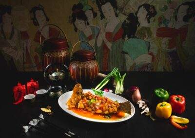 A plate of chinese food on a table in front of a painting.