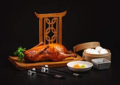 A chinese roasted duck on a wooden stand with chopsticks.