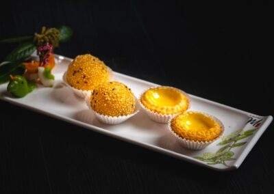 Three desserts on a white plate with a flower in the middle.