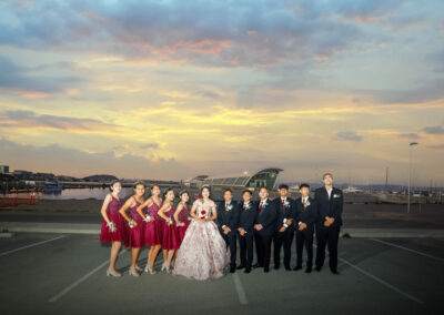 A group of bridesmaids and groomsmen standing in a parking lot.