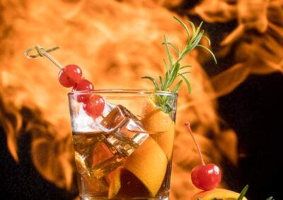 A glass of whiskey on fire in front of a black background.