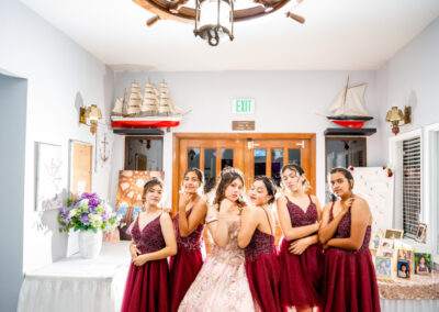 A group of bridesmaids posing in front of a ship wheel.