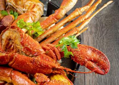 A plate with lobster, corn, and a glass of wine.