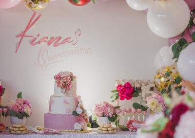 A pink and white birthday party with balloons and decorations.