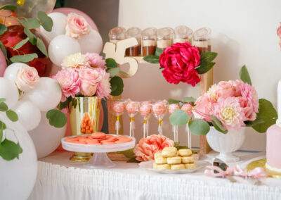 A pink and gold birthday party with flowers and desserts.