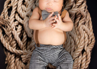 A baby sleeping in a rope on a black background.