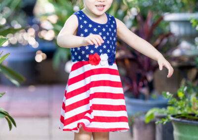 A little girl in a red, white and blue dress.